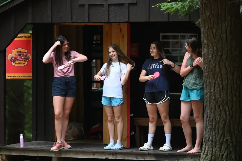 Four campers standing on the porch of a wooden cabin